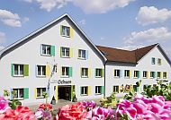Hotel Ochsen, Außenansicht, Hotel Ochsen Kißlegg mit blühenden Blumen im Vordergrund.