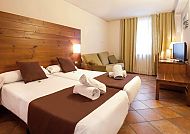 Gemütliches Hotelzimmer mit Doppelbett, Sofa und warmer Beleuchtung