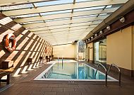 Heller Innenpool mit Glasdach und Holzwänden, ruhige Atmosphäre.