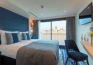 Moderne Kabine mit Doppelbett, Blick auf Fluss und Stadt.